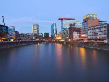 Düsseldorf, Almanya - Şafakta güzel aydınlatılmış Medienhafen. Mavi saatte şehir manzarası..