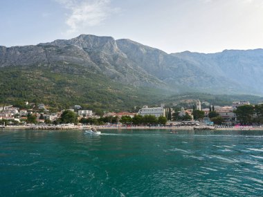 Baska Voda, Hırvatistan - 25 Temmuz 2021. Şehrin ve denizden Biokovo Dağı 'nın muhteşem panoramik manzarası. Ön plandaki ana kumsal..
