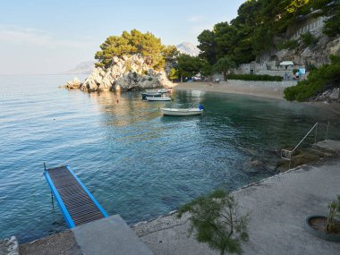 Hırvatistan 'ın Brela tatil beldesinde çam ağaçlarıyla çevrili Paradise Beach Podrace. Güzel Adriyatik Denizi manzarası.