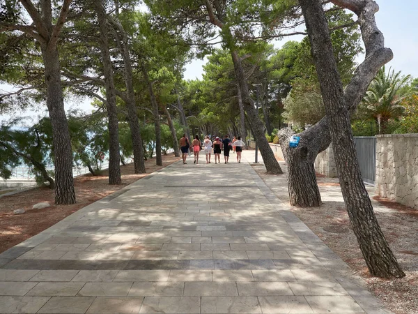 Bol, Hırvatistan - 25 Temmuz 2021. Brac adasındaki Zlatni Rat plajına giden gezinti alanındaki turistler.