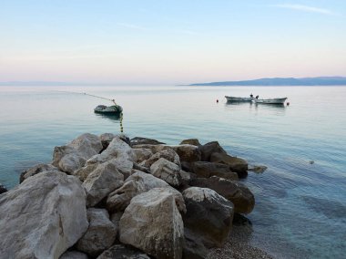 Brela, Hırvatistan - 24 Temmuz 2021: Sabahleyin bir sahil beldesinde sakin Adriyatik Denizi. Denizdeki demirli tekneler. Güzel Deniz Manzarası.