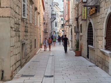 Makarska, Dalmaçya, Hırvatistan - 20 Temmuz 2021: Tarihi binaları olan eski Hırvat kasabasının dar sokakları. Yürüyen turistler.