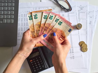 Avro nakitini tutan bir kadının resmi. Aylık giderlerini hesaplamak için hesap makinesi kullanan bir kadın. Finansal danışman çalışıyor..