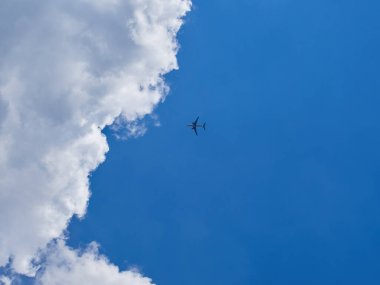 Mavi gökyüzünde uçan uçağın alt görüntüsü. Fırıl fırıl dönen bulutlarda uçan bir uçak. Mavi gökyüzü ve beyaz bulutlar.