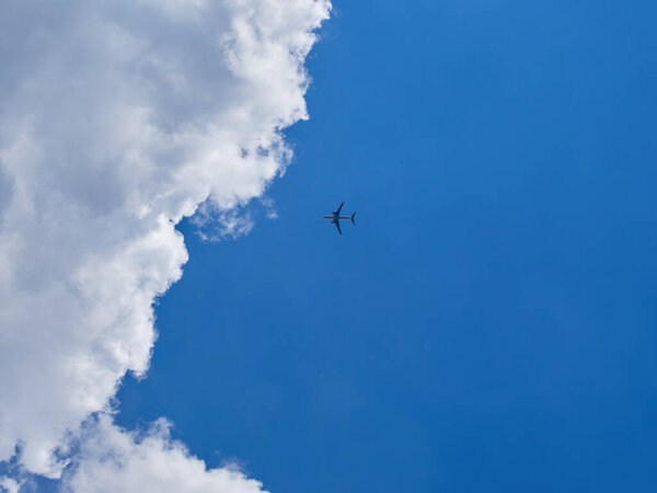 Bottom view of the plane flying in the blue sky. Airliner flying in swirling clouds. Blue sky and white clouds.