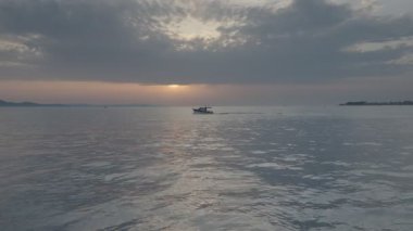 Zadar, Hırvatistan 27 Temmuz 2021: Adriyatik Denizi üzerindeki ünlü günbatımı manzarası Zadar kentindeki gezinti güvertesinden görülmektedir. Denizde yüzen gemiler.