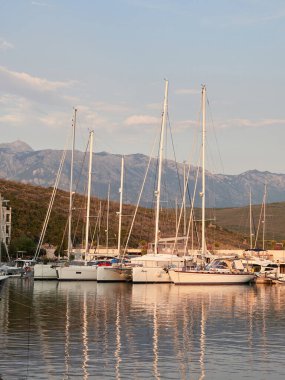 Lustica Bay, Montenegro: 17 July 2022 - Luxurious marina with moored yachts and the village of Lustica at sunset. 