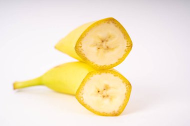 Beyaz arka planda üst üste iki muz parçası uzanır.