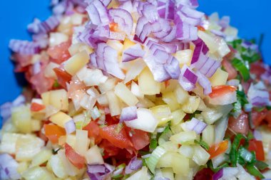 Taze ve lezzetli salata, doğranmış kırmızı soğan, taze soğan, sarı biber ve domatesler mavi kasede.