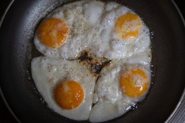 Tavada kızarırken tuzlu ve biberli dört yumurta.