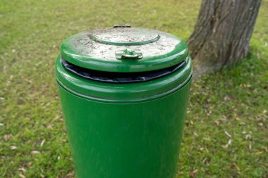 Parkta yeşil yuvarlak metal çöp tenekesi