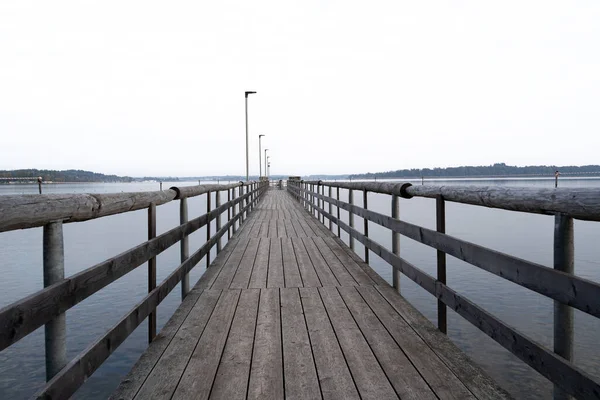 Bulutlu bir sonbahar sabahında gölde uzun bir ahşap iskele.