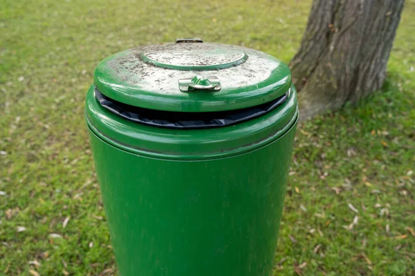 Parkta yeşil yuvarlak metal çöp tenekesi