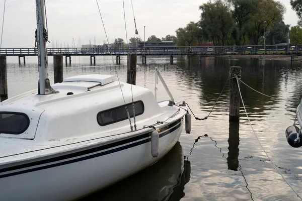秋の朝に湖の木の柱に結びつけられた帆船 — ストック写真