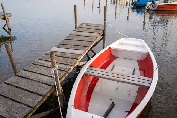 湖に浮かぶ木製の桟橋には白と赤のボートが停泊していた — ストック写真