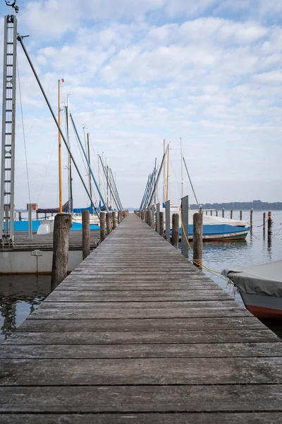 秋の朝 駐車場と屋根付きの帆船で湖の上の木製の桟橋 — ストック写真
