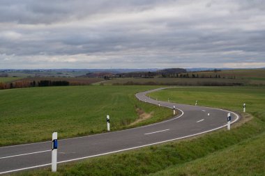 Curvy country road with cloudy sky in autumn