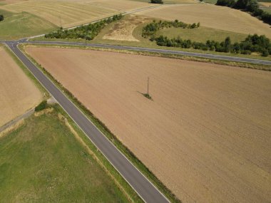 Aerial view of agriculture fields with asphalt roads in summer 
