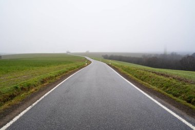 Sisli bir sonbahar sabahında uzun asfalt köy yolu