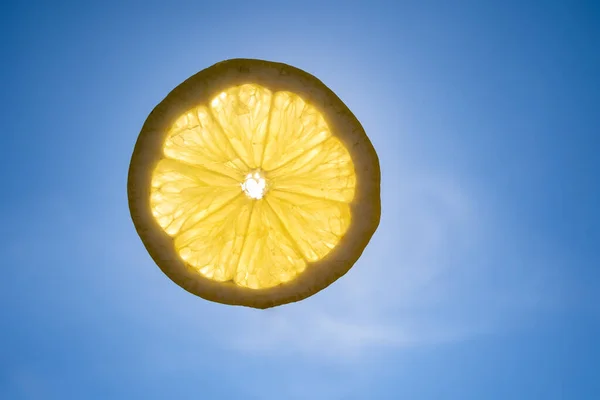 Slice of lemon in the blue sunny sky
