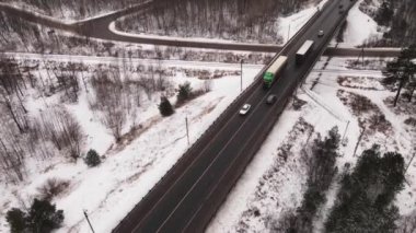 Kışın köprüden geçen kamyonlar ve arabalarla otoyol, hava manzarası.