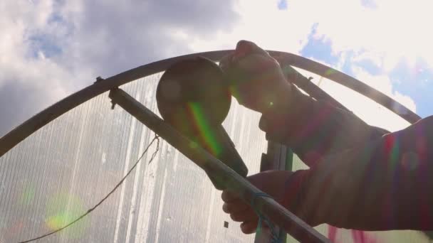 Las manos de un hombre están cortando un invernadero de metal oxidado con una amoladora angular. — Vídeos de Stock