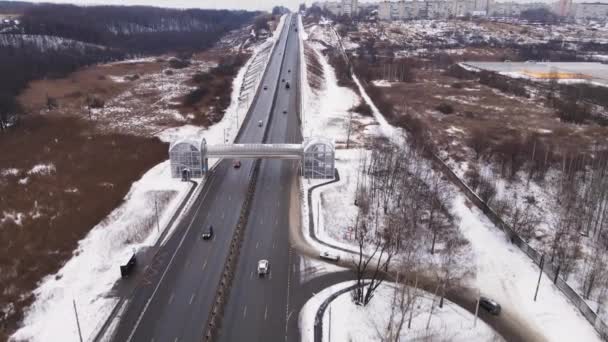Country highway with an overhead pedestrian crossing in winter, aerial view. — Stock Video