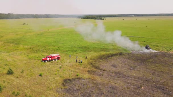 Vid kanten av ett bränt fält häller en brandman vatten över varandra.. — Stockvideo