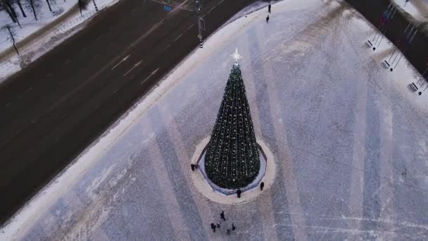 Újévi fa világító koszorúkkal a város főterén, légi felvétel. — Stock videók
