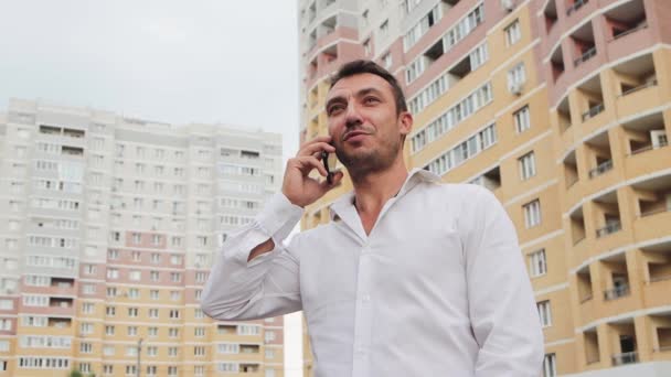 Un homme d'affaires en chemise blanche parle au téléphone avec un sourire. — Video