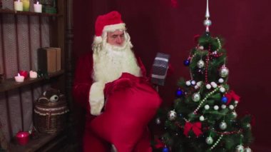 Modern Noel Baba kırmızı bir çantadan hediye alır.