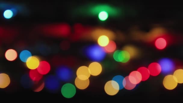 Luces multicolores sobre un fondo negro parpadean suavemente, copian espacio. — Vídeos de Stock