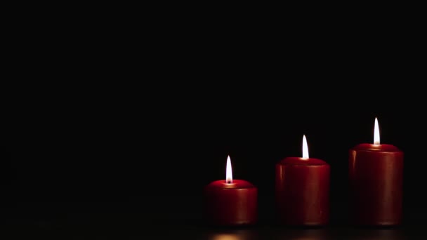 Tre candele rosse misteriosamente accese su uno sfondo nero. Copia spazio. — Video Stock