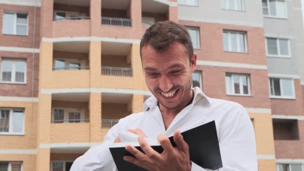 Gros plan d'un homme d'affaires enthousiaste riant à travers un carnet. — Video