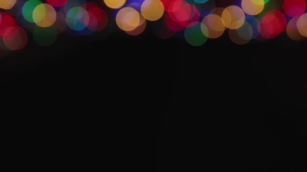 Above, colored lights flicker out of focus against a black background. — Stock Video