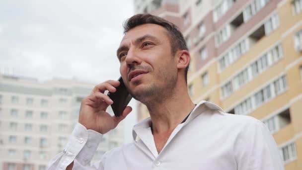 Un bell'uomo d'affari parla al telefono con un sorriso. — Video Stock