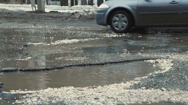 Grote kuilen op het asfalt, wegeninfrastructuur beschadigd na regen. — Stockvideo