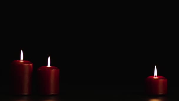 Drei rote brennende Kerzen auf schwarzem Grund. Kopierraum. — Stockvideo