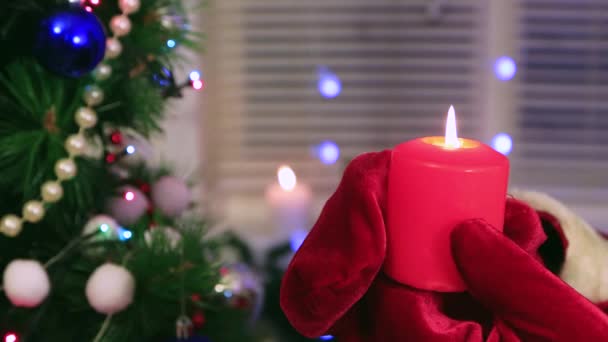 Zbliżenie Santa Clauss ręce trzymając płonącą czerwoną świecę. — Wideo stockowe