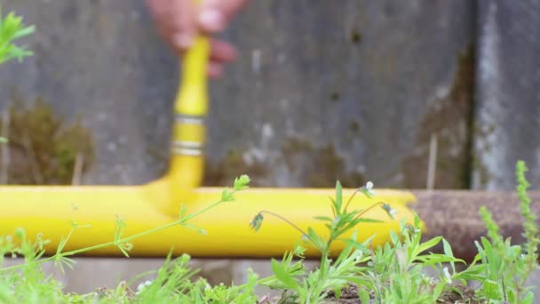 Eine Hand mit einem Pinsel in Großaufnahme bemalt ein rostiges Rohr mit gelber Farbe. — Stockvideo