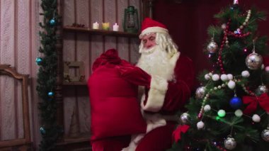 Modern Noel Baba kırmızı bir çantayı hediyelerle çözer..