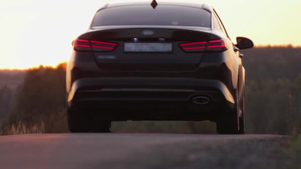 L'auto guida verso il tramonto, la luce della sera si riflette nell'asfalto. — Video Stock