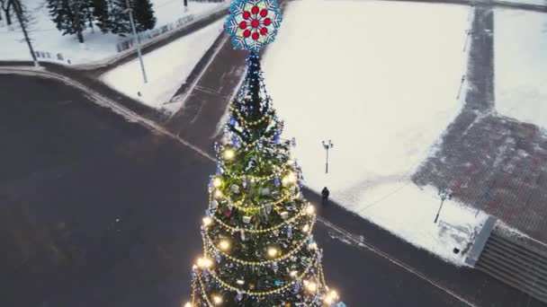 Un sapin de Noël mince et lumineux sur la place de la ville, vue aérienne. — Video