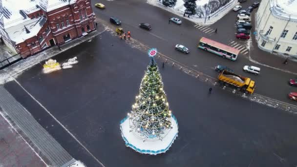 Luxus karácsonyfa ragyogó koszorúkkal a város főterén, légi felvétel. — Stock videók