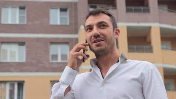 Närbild av en lycklig affärsman som pratar i telefon med ett leende. — Stockvideo