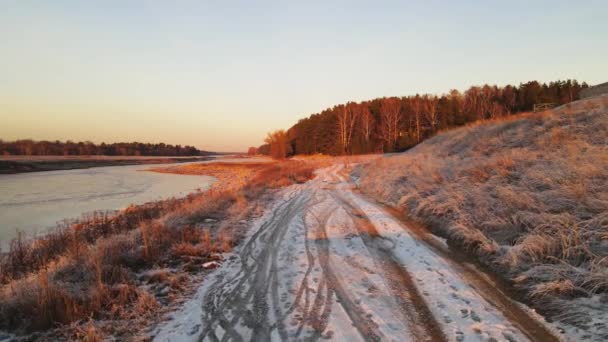 La hierba y el camino junto al río están cubiertos de heladas blancas, vista aérea. — Vídeo de stock
