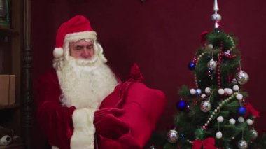 Mutlu büyükbaba Noel ağacının yanındaki sandalyede. Yeni 