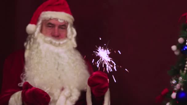Close-up Papai Noel segura um sparkler ardente em sua mão e parabéns. — Vídeo de Stock
