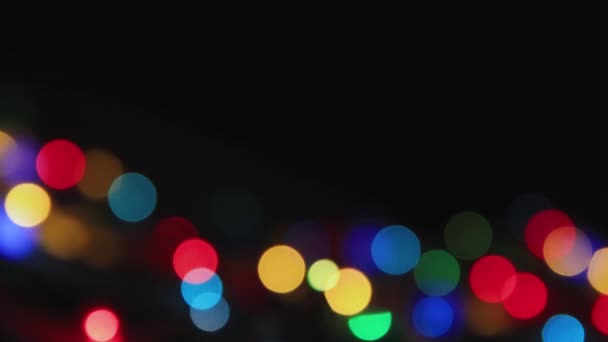 Luzes multi-coloridas cintilam suavemente em um fundo preto, espaço de cópia. — Vídeo de Stock