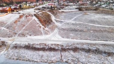 Tarla, yamaç ve köyün karların altında güneşin turuncu ışığında.